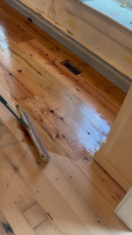 Partially finished pine floor with tools visible near a doorway.